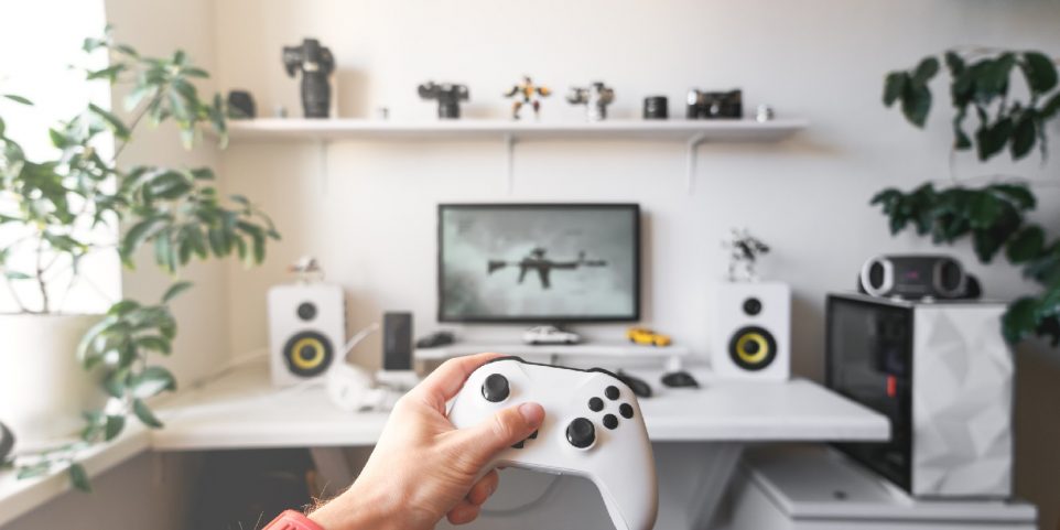Close-up of male hands holding white wireless gamepad against white computer dream desk