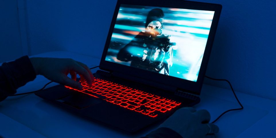 Close up of man playing on gaming laptop at night