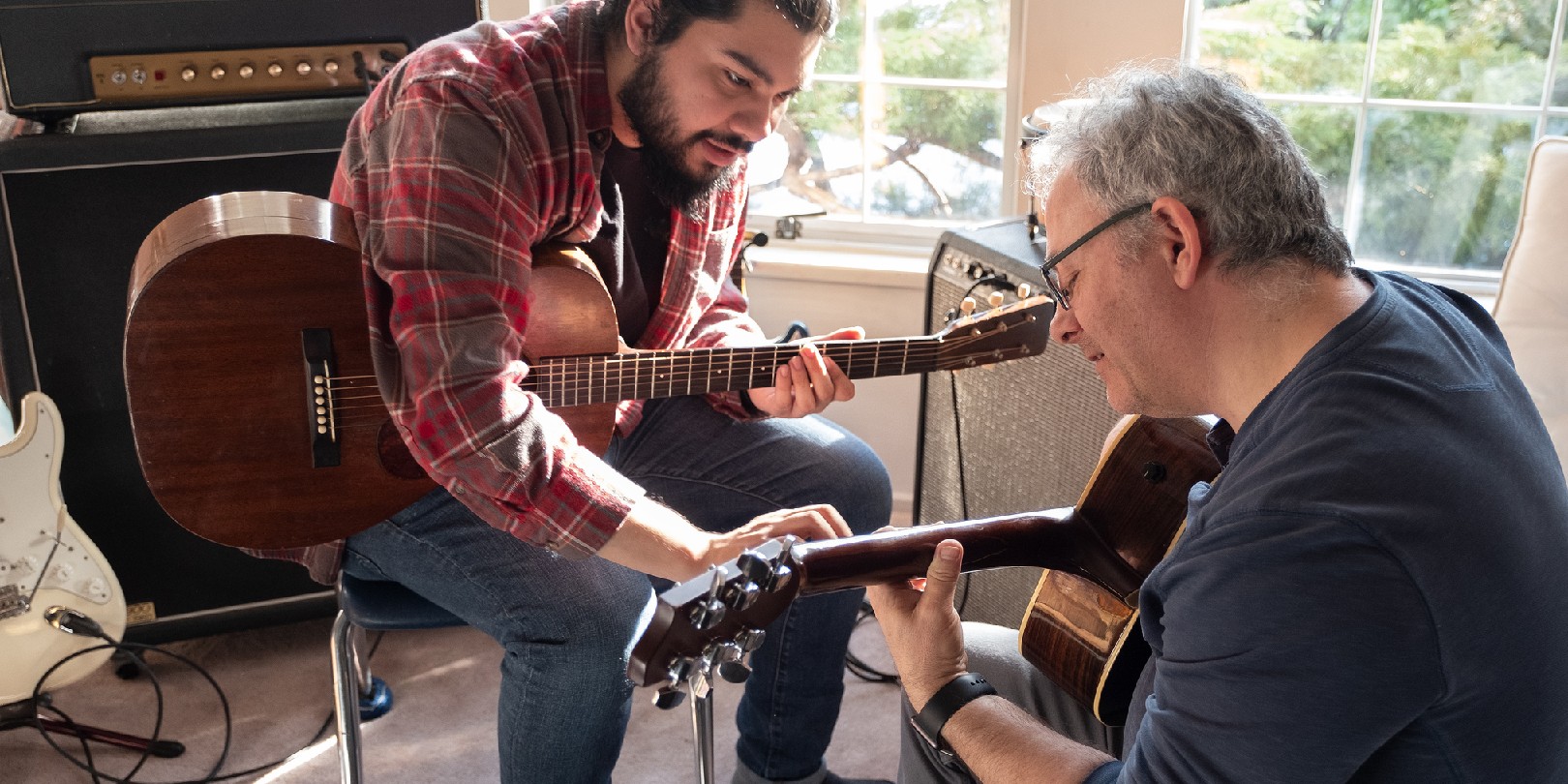 Hispanic Young Man Teaching Mature Caucasian Man to Play Guitar